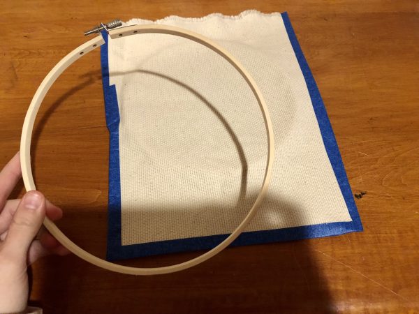 Steps for adorable DIY phone pad made by a punch needle with acrylic yarn.  Punch needle. Punch needle kit. Embroidery Hoop. Monks cloth. Fabric Scissors. Grey, Yellow, and White color scheme. Yarn crafts. Punch needle projects. Phone holder on desk. DIY phone holder.