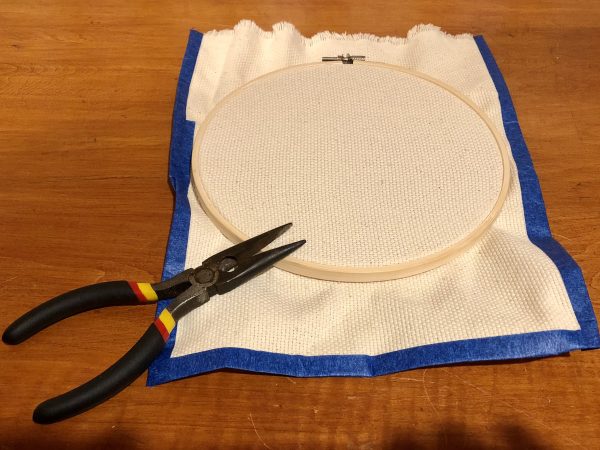 Steps for adorable DIY phone pad made by a punch needle with acrylic yarn.  Punch needle. Punch needle kit. Embroidery Hoop. Monks cloth. Fabric Scissors. Grey, Yellow, and White color scheme. Yarn crafts. Punch needle projects. Phone holder on desk. DIY phone holder.