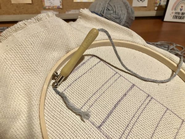 Steps for adorable DIY phone pad made by a punch needle with acrylic yarn.  Punch needle. Punch needle kit. Embroidery Hoop. Monks cloth. Fabric Scissors. Grey, Yellow, and White color scheme. Yarn crafts. Punch needle projects. Phone holder on desk. DIY phone holder.