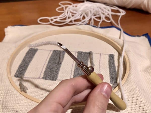 Steps for adorable DIY phone pad made by a punch needle with acrylic yarn.  Punch needle. Punch needle kit. Embroidery Hoop. Monks cloth. Fabric Scissors. Grey, Yellow, and White color scheme. Yarn crafts. Punch needle projects. Phone holder on desk. DIY phone holder.