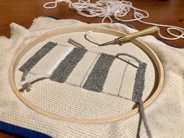 Steps for adorable DIY phone pad made by a punch needle with acrylic yarn.  Punch needle. Punch needle kit. Embroidery Hoop. Monks cloth. Fabric Scissors. Grey, Yellow, and White color scheme. Yarn crafts. Punch needle projects. Phone holder on desk. DIY phone holder.