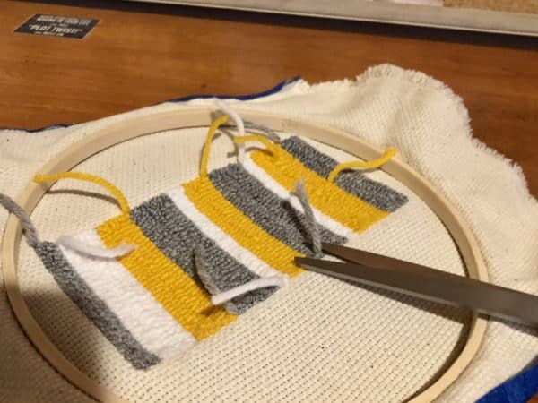 Steps for adorable DIY phone pad made by a punch needle with acrylic yarn.  Punch needle. Punch needle kit. Embroidery Hoop. Monks cloth. Fabric Scissors. Grey, Yellow, and White color scheme. Yarn crafts. Punch needle projects. Phone holder on desk. DIY phone holder.