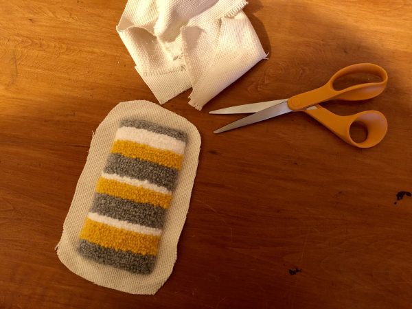 Steps for adorable DIY phone pad made by a punch needle with acrylic yarn.  Punch needle. Punch needle kit. Embroidery Hoop. Monks cloth. Fabric Scissors. Grey, Yellow, and White color scheme. Yarn crafts. Punch needle projects. Phone holder on desk. DIY phone holder.